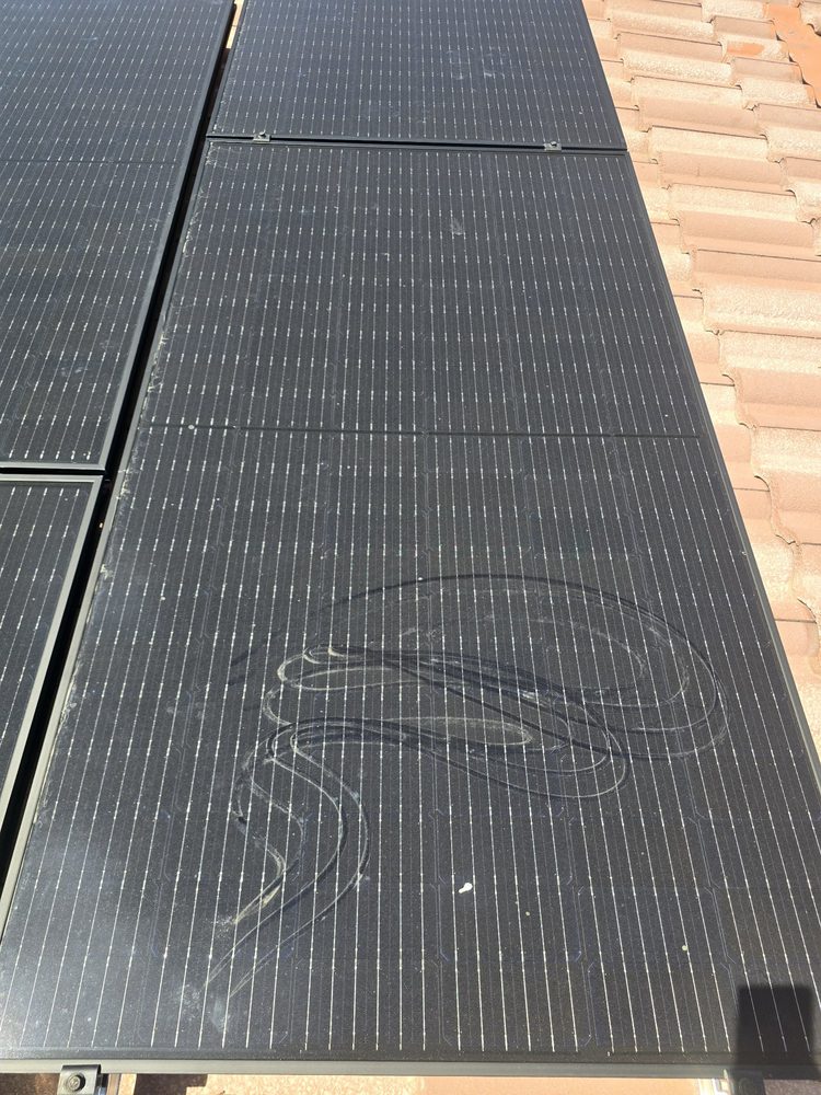 A solar panel mid-clean, dust wiping away in a swirl to reveal clean glass