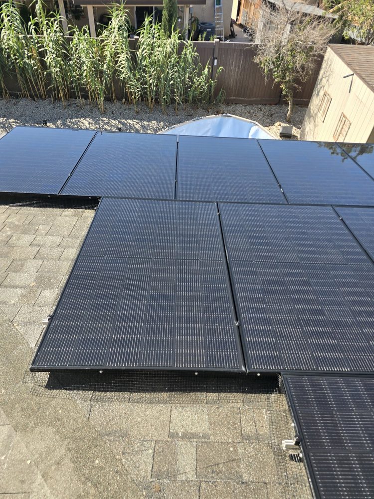 A clean, glossy solar array seen from above after cleaning, with the backyard below