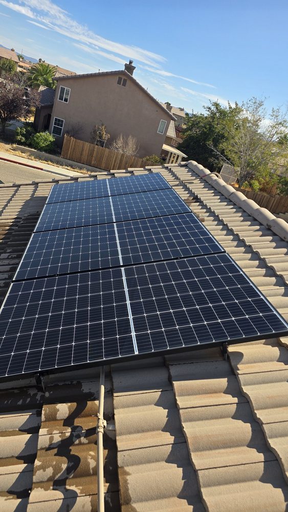 A clean deep-blue solar array on a tile roof after cleaning, the tiles still wet from the wash