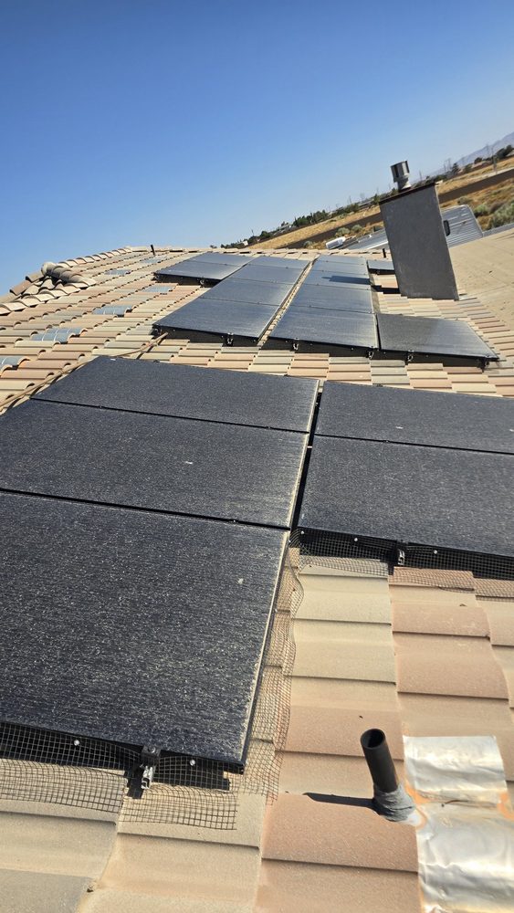 Solar panels dulled by a film of dust on a beige tile roof before cleaning