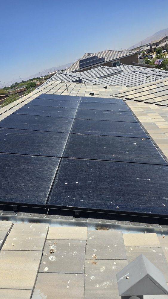 Dusty solar panels with bird spots on a grey tile roof before cleaning